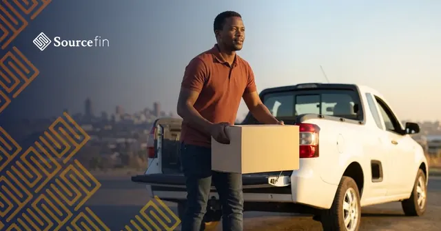 Gauteng SMME owner unloading delivery boxes from his bakkie with the Johannesburg skyline behind him